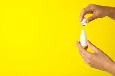 Beyaz ilaç şişesi kadınların elinde sarı arka planda, mesaj için boşluk