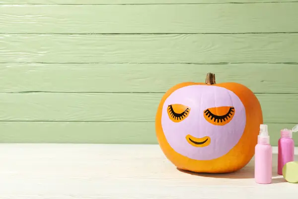 Skin and face care concept - pumpkin with face mask