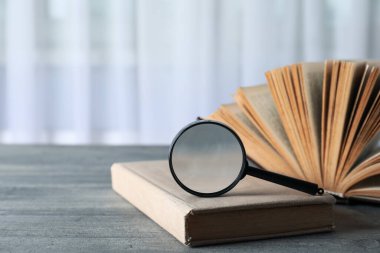 Büyüteç ve kitaplar ahşap masa üzerinde hafif arkaplan, metin için boşluk