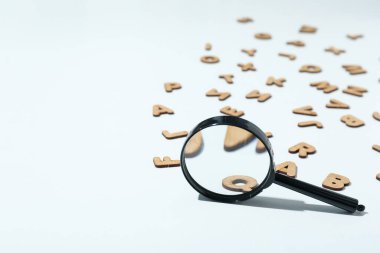 Beyaz arkaplanda büyüteç ve ahşap harfler, metin için boşluk