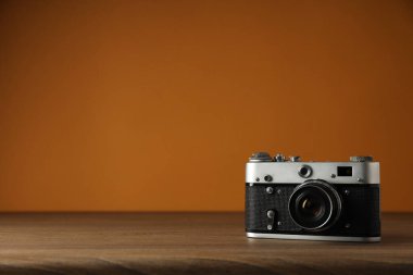 Kahverengi arkaplandaki ahşap masadaki klasik kamera, metin için boşluk