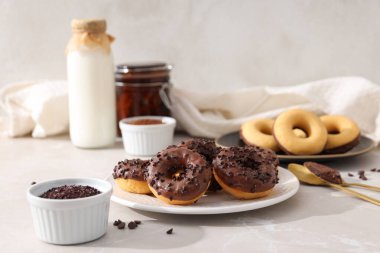 Tabaklarda çikolatalı çörekler, çatal bıçak takımı, süt şişesi ve arka planda kaseler.