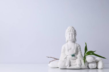 Buda heykeli, beyaz arkaplanda taşlar ve yapraklar, metin için boşluk