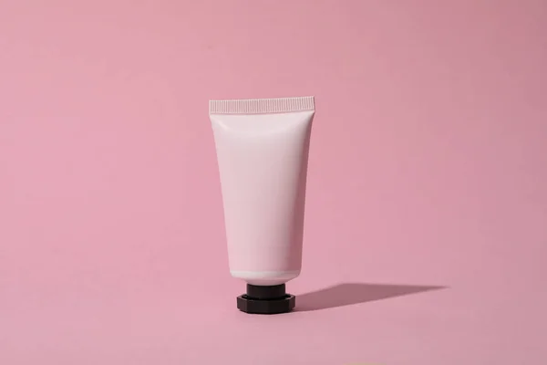 Pink tube with cream on pink background