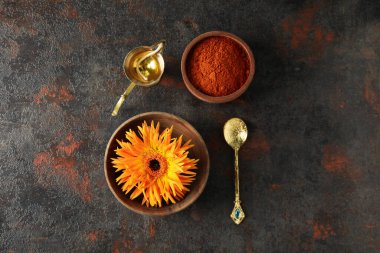 Baharat ve çiçekli ahşap kaseler, bakır oryantal şamdan ve koyu arka planda kaşık, üst manzara