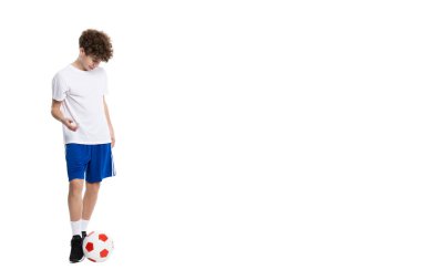 Beyazların arka planında izole bir şekilde futbol oynayan genç bir çocuğun resmi..