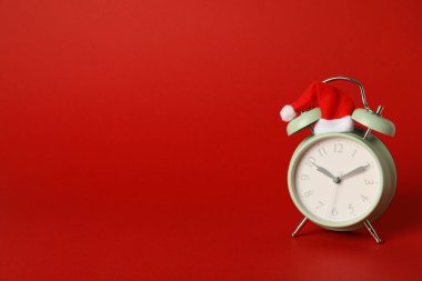 Kırmızı arka planda Noel Baba şapkalı bir saat..