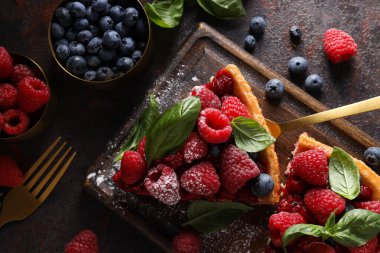 Böğürtlenli turta gemide, böğürtlenler kaselerde koyu gri arka planda, üst manzara