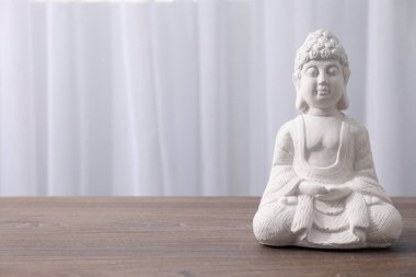 Beyaz Buddha heykeli ahşap masa üzerinde ışık arkaplan, metin için boşluk