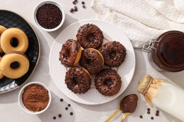 Tabaklarda çikolatalı çörekler, çatal bıçak takımı, süt şişesi ve ışık arka planında kavanoz, üst manzara.