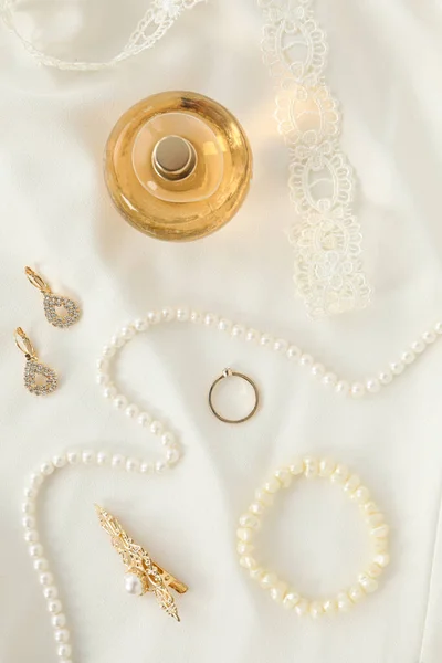 Wedding jewelry and perfume on light background, top view