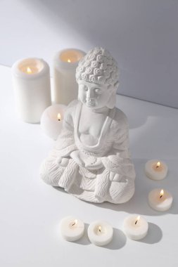 Buda heykeli ve beyaz arkaplanda mumlar