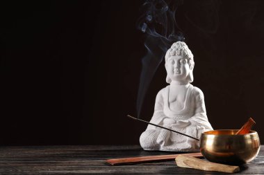 Buda heykeli, tütsü çubuğu, duman ve kase koyu kahverengi arka planda, metin için boşluk