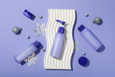 Mor arka planda kozmetik şişeler ve dekorasyonlar, üst görünüm