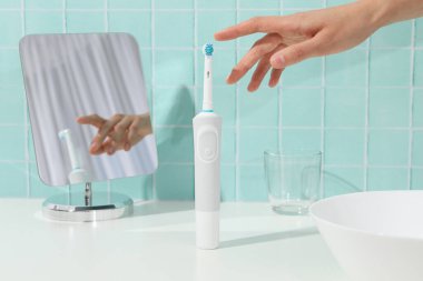 Elektrikli diş fırçası, ayna, cam ve el mavi arkaplanda.