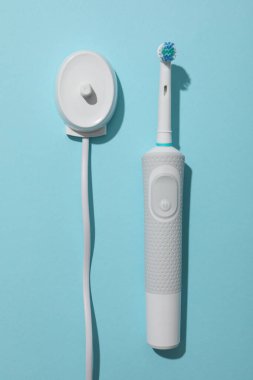 Mavi arkaplanda elektrikli diş fırçası, üst görünüm