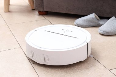 Kablosuz elektrik süpürgesi ve bej arka planda terlikler, kapatın.