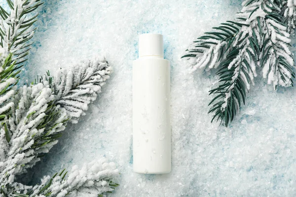 Kozmetik şişesi, köknar dalları ve arka planda kar, üst görünüm