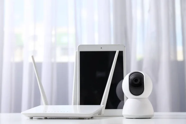 Wi-Fi router, home security camera and tablet on light background