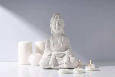 Buda heykeli ve beyaz arkaplanda mumlar