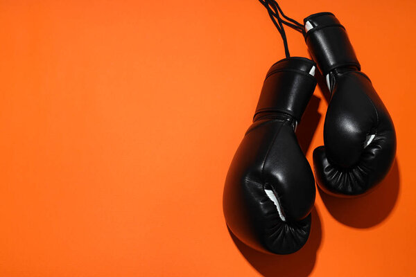 Черные боксерские перчатки на оранжевом фоне