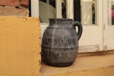 Turuncu duvar, tuğla, pencere ve sürahi.