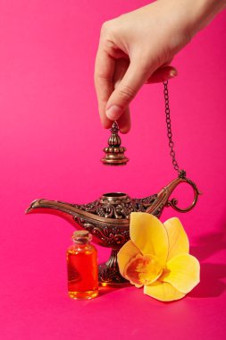 Bakır çaydanlık, yağ şişesi, çiçek ve el pembe arka planda, kapat