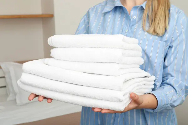 Neatly folded white towels in the hands of a woman