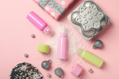 Kozmetik şişeleri ve kavanozlar, hediye kutusu ve pembe arka planda kar, üst manzara.