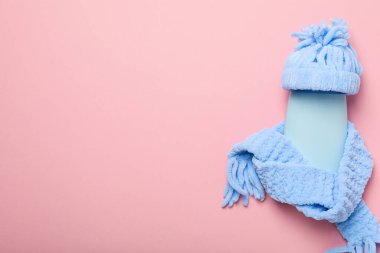 Pembe arka planda kapak ve eşarplı kozmetik tüp, metin için boşluk