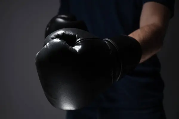 A man in a black T-shirt and boxing gloves