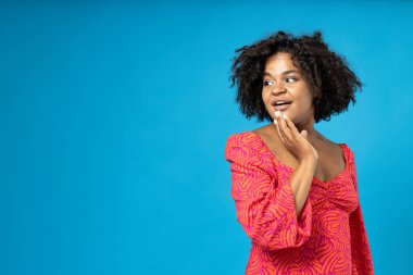 Mavi arka planda şaşırmış kıvırcık kız, mesaj için yer