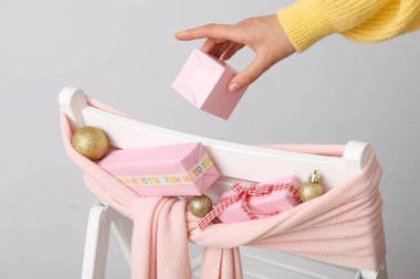 Sandalye, hediye kutuları ve gri arka planda kadın eli.