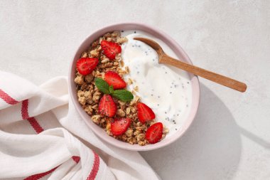 Yoğurtlu kase, arka planda kaşık ve havlu, üst manzara.