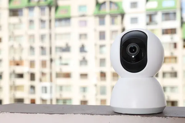 Home security camera against background of houses, space for text