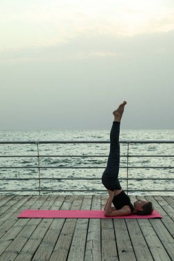 Yoga minderinde bir kadın, ahşap zeminde denizde, metin için yer.