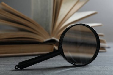 Büyüteç ve açık kitap ahşap masa üzerinde ışık arkaplan, kapatın