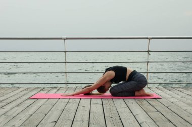 Yoga minderinde bir kadın Denizde ahşap zeminde
