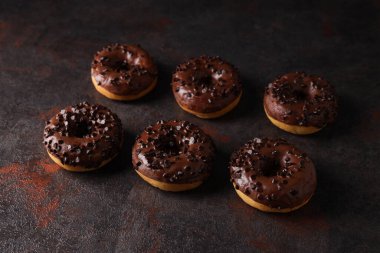 Koyu gri arka planda çikolata parçalı donutlar.