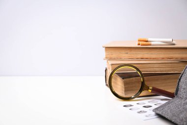 Beyaz zemin üzerine kitap ve şapka ile büyüteç