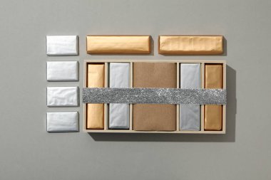 Folyodaki çikolatalar ve gri arka planda kurdeleli kutular, üst görünüm