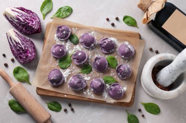 Mutfak tahtasında mor hamur tatlısı, hafif arka planda lahana ve baharatlar, üst manzara.