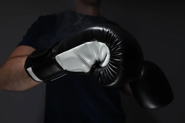 A man in a black T-shirt and boxing gloves