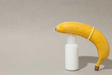 Kayganlaştırıcı, kondomda muz, gri arka planda..