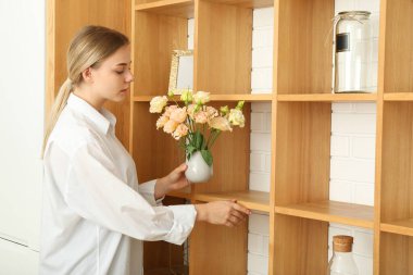 Elinde çiçekli vazo tutan bir kadın var.