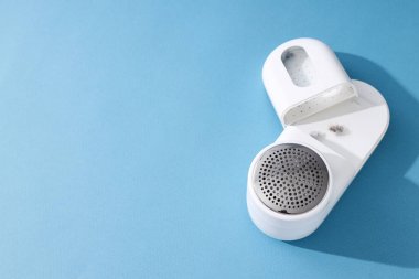 Elbiselerin üzerine kumaş traş makinesi, mavi arka plan..