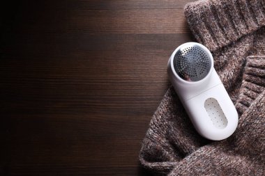 Elbiselerin üzerine kumaş traş makinesi, koyu bir arkaplan.