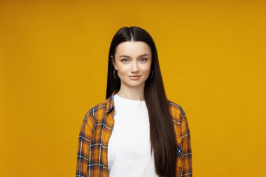 Sarı arka planda poz veren çekici genç bir kadın.