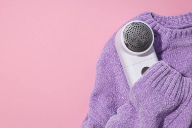 Pembe arka planda kumaşları traş eden bir makine..