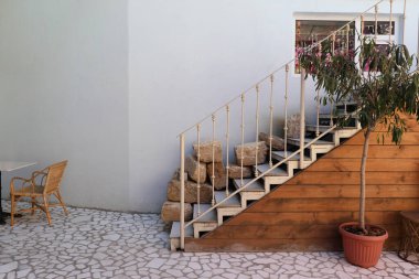 Merdiven, saksıdaki ağaç ve açık kafedeki sandalyeli masa.